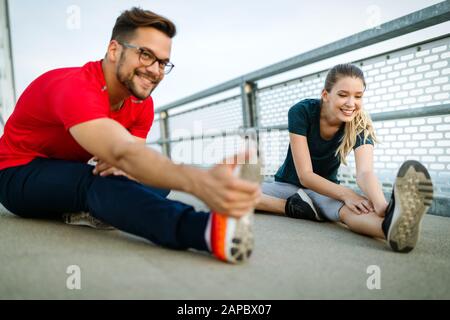 Fitness, sport, training and lifestyle concept. Fit couple friends stretching outdoors Stock Photo
