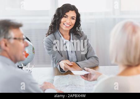 Woman giving tickets to happy mature couple Stock Photo