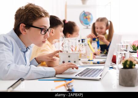 Creating robots. Concentrated boy typing on laptop Stock Photo