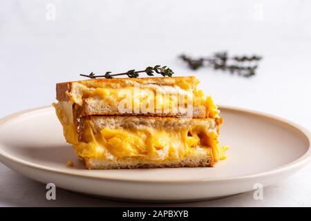 Scrambled egg sandwich with cheese, hearty homemade breakfast on white table Stock Photo