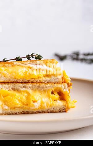 Scrambled egg sandwich with cheese, hearty homemade breakfast on white table Stock Photo