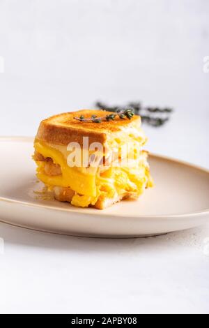 Scrambled egg sandwich with cheese, hearty homemade breakfast on white table Stock Photo