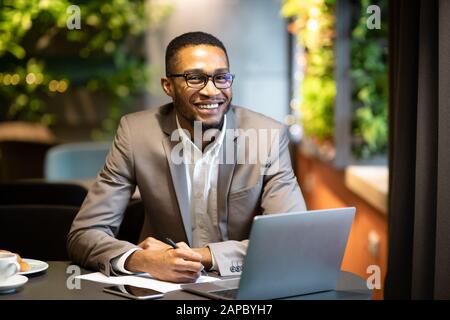 Black business guy taking notes in notebook Stock Photo