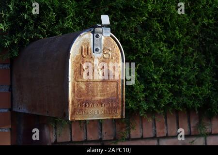 Mailbox US Mail rusty American design on a street in Granada next to a green hedge Stock Photo