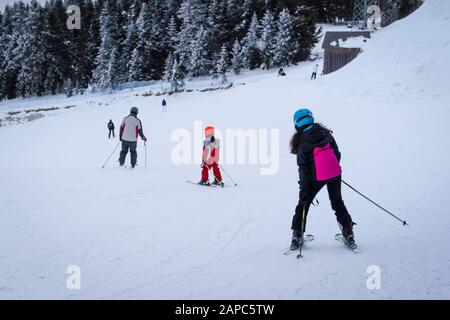 Back view of family ski together, father, mother and daughter. Mom, dad and girl. Stock Photo