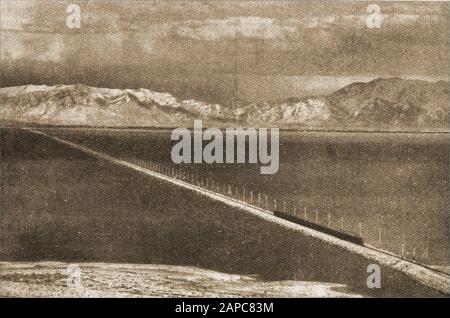 A  vintage magazine photo showing a train (Bottom right) crossing the Lucin Cutoff trestle , a 12-mile (19 km) long railroad trestle crossing the Great Salt Lake. It was used between,  1904 and the 1950's, when it was replaced by a rock and dirt causeway. Stock Photo