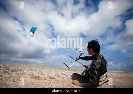 A man preparing for kitesurfing on the beach of the North Sea in Denmark, Kite surfer holding onto control bar Stock Photo