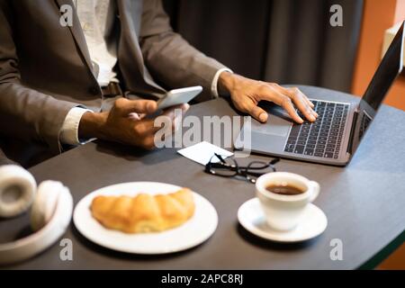 Cropped image of busy afro guy using phone and computer Stock Photo