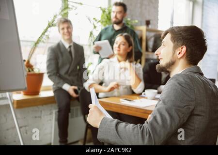 For ideas. Group of young business professionals having a meeting. Diverse group of coworkers discuss new decisions, plans, results, strategy. Creativity, workplace, business, finance, teamwork. Stock Photo