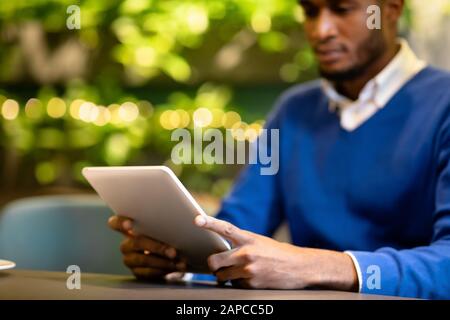 Black guy sitting in coffee shop working on tablet Stock Photo