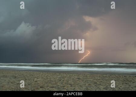 Lightning bolt strikes in the water from a thunderstorm over sea Stock Photo