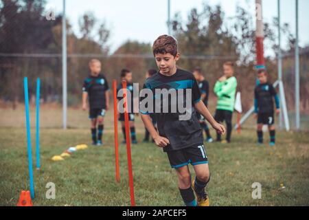 Soccer Drills: The Slalom Drill. Youth soccer practice drills. Young football player training on pitch . Soccer slalom cone drill. Boy in soccer jerse Stock Photo