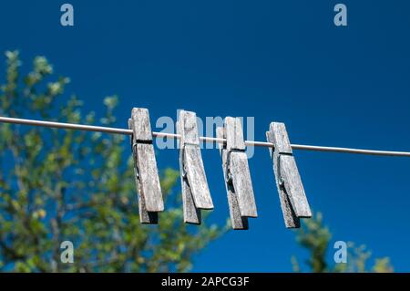 Weathered wooden laundry clamps hanging on a string on blue sky background Stock Photo