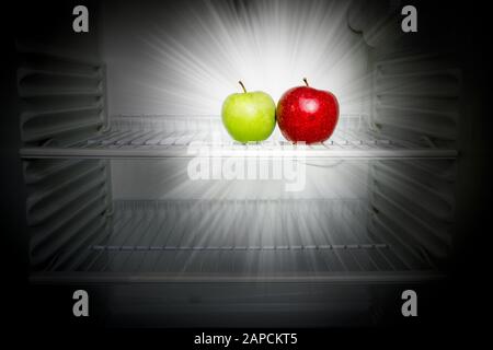 Conceptual creative photo of glowing in the dark fresh red and green apples in an open empty refrigerator. Weight loss diet concept. Stock Photo