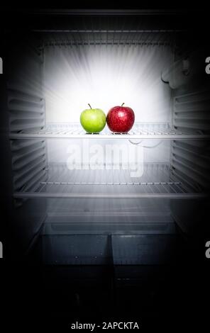 Conceptual creative photo of glowing in the dark fresh red and green apples in an open empty refrigerator. Weight loss diet concept. Stock Photo