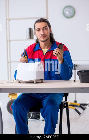 The young male contractor repairing toaster at workshop Stock Photo