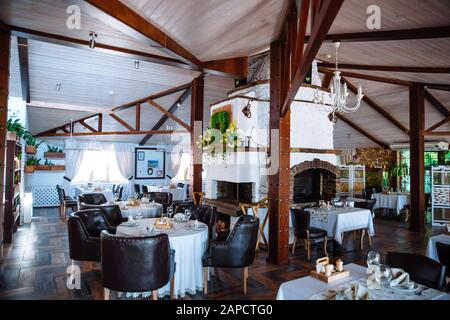 Restaurant interior with a stone stove in the middle of the hall. In the hall there are served tables with soft chairs. Stock Photo