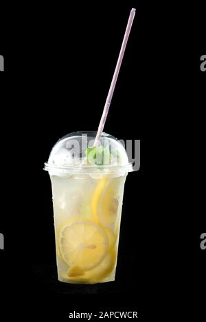 Cold refreshing drink lemonade or mojito cocktail with lemon and mint. There's a drinking straw in the glass. Isolated on black background. Stock Photo