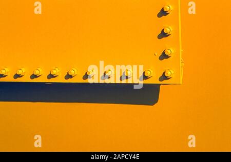 Nuts and bolts on a yellow metal plate Stock Photo