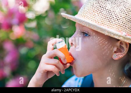 Girl having asthma using asthma inhaler for being healthy - shallow depth of field Stock Photo