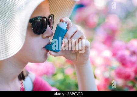 Girl having asthma using asthma inhaler for being healthy - shallow depth of field Stock Photo