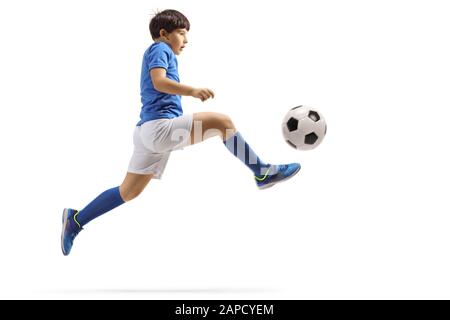 Full length profile shot of a boy jumping and kicking a soccer ball isolated on white background Stock Photo