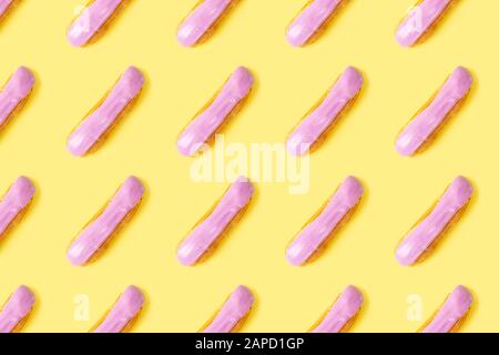 Flat lay with arranged homemade eclairs pattern with blackberries and blueberries on yellow background Stock Photo