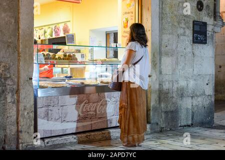 A young woman orders food from a sidewalk cafe display in the Diocletian's Palace section of the ancient city of Split, Croatia Stock Photo