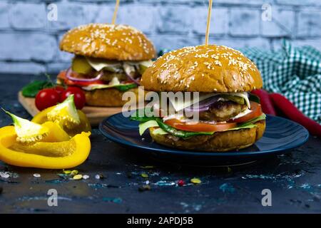 Two homemade beef burgers with mushrooms, micro greens, red onion, fried eggs and beet sauce on wooden cutting board Stock Photo
