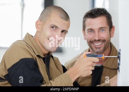 portrait of two contractors working indoors one using screwdriver Stock Photo