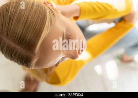 Concentrated lady in yellow jumper posing for camera at home Stock Photo