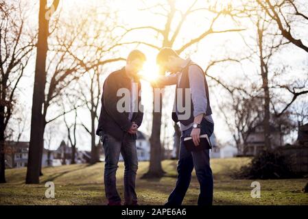 Men discussing the bible in a garden under sunlight with a blurry background Stock Photo