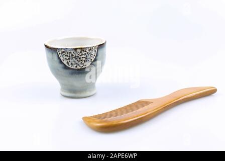 Chinese comb and a teacup on a white surface Stock Photo
