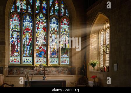 St Michael and All Angels Church altar and stained glass window. Withington, Gloucestershire, England Stock Photo