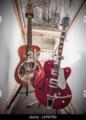 vintage guitars on stands near window Stock Photo