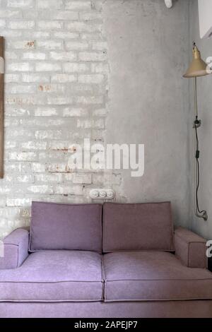 Pink sofa against white brick and plastered wall Stock Photo