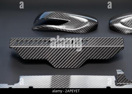 A close-up on a car exterior elements made from carbon fiber of interwoven black and gray color from heavy-duty yarns for the production of light and Stock Photo