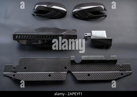 A close-up on a car exterior elements made from carbon fiber of interwoven black and gray color from heavy-duty yarns for the production of light and Stock Photo