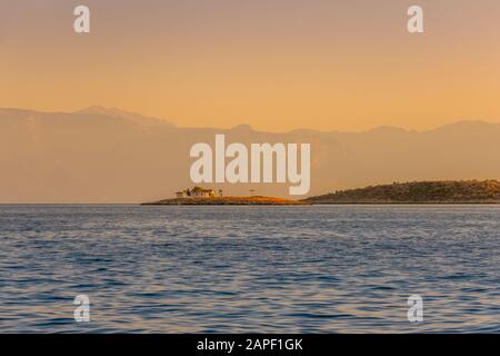 Greece. The hilly coast of the Gulf of Corinth. Summer sunset. Lonely little church on the shore Stock Photo