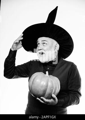 Senior man white beard celebrate Halloween with pumpkin. Wizard costume hat Halloween party. Magician witcher old man. Magic concept. Experienced and wise. Halloween tradition. Cosplay outfit. Stock Photo