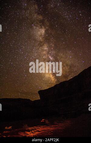 The Milky Way shines bright in the night sky over the rim of the canyon in Canyonlands National Park. Stock Photo