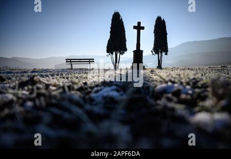 Hechingen, Germany. 22nd Jan, 2020. The sun shines behind a wayside cross on a field covered with frost. Credit: Sebastian Gollnow/dpa/Alamy Live News Stock Photo