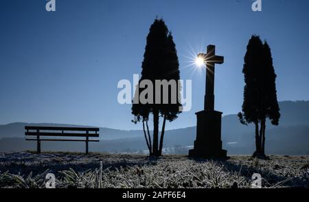 Hechingen, Germany. 22nd Jan, 2020. The sun shines behind a wayside cross on a field covered with frost. Credit: Sebastian Gollnow/dpa/Alamy Live News Stock Photo