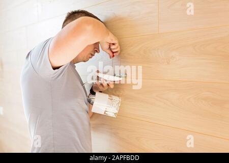 Closeup white tile on the wall of drywall without grout and electrical wires, scaffold, bucket with adhesive. Concept of repair in bathroom, toilet, k Stock Photo