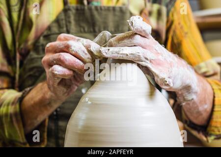 Potter master working on potter's wheel, making new bowl from raw clay Stock Photo