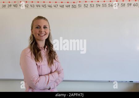 Female teacher with long blonde hair standing at a white board Stock Photo