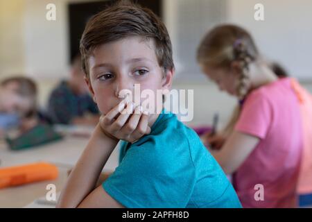 Schoolboy sitting at a desk in an elementary school classroom Stock Photo