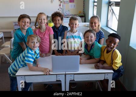 Group of schoolchildren using a laptop computer in an elementary school classroom Stock Photo
