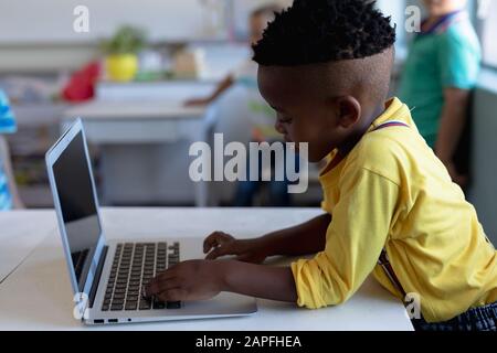 Schoolboy using a laptop computer in an elementary school classroom Stock Photo