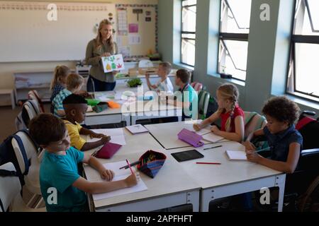 Female primary school teacher standing in a classroom gesturing to